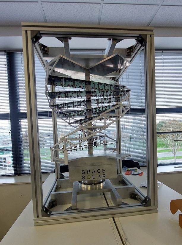 A metal and glass box about one metre across and one-and-a-half tall. It contains a spiral structure holding several electronic circuit boards arranged around the spiral.

