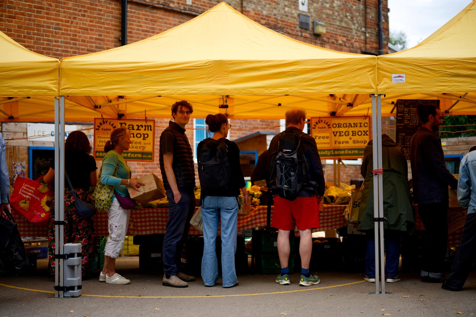 Queue of customers at a veg stall under a gazebo