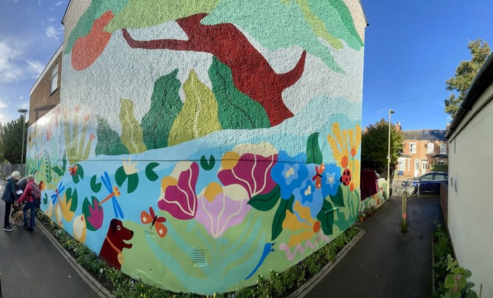 A panoramic view of a mural with bold colourful figures of plants and animals