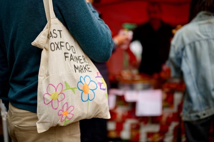 A market customer with a tote bag that says East Oxford Farmers Market
